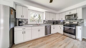 A modern kitchen with white cabinets, a stainless steel refrigerator, a built-in oven, and a microwave. - Home < 1 Mi to Lake Erie & Shades Beach Park! (Harborcreek)