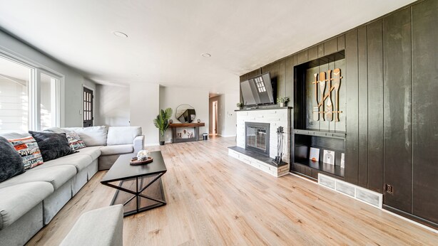 A modern living room with a sectional sofa, a coffee table, a fireplace, and a TV mounted on the wall. - Home < 1 Mi to Lake Erie & Shades Beach Park! (Harborcreek)