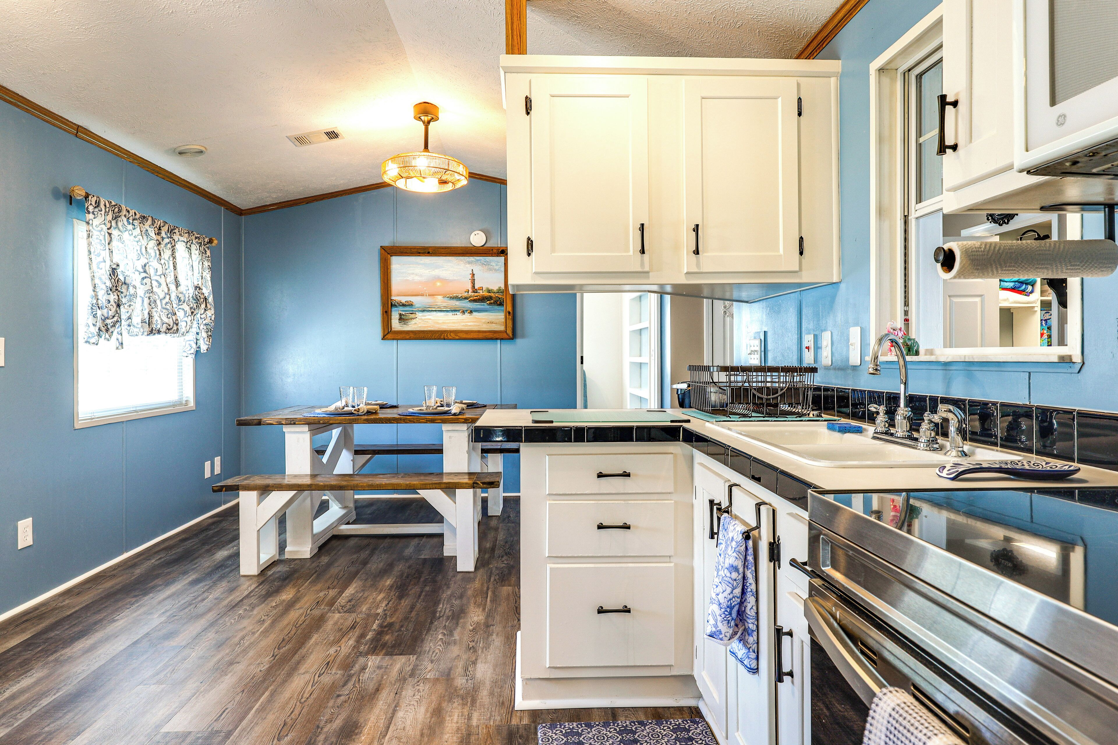 A kitchen with white cabinets, a stainless steel sink, and a wooden bench.