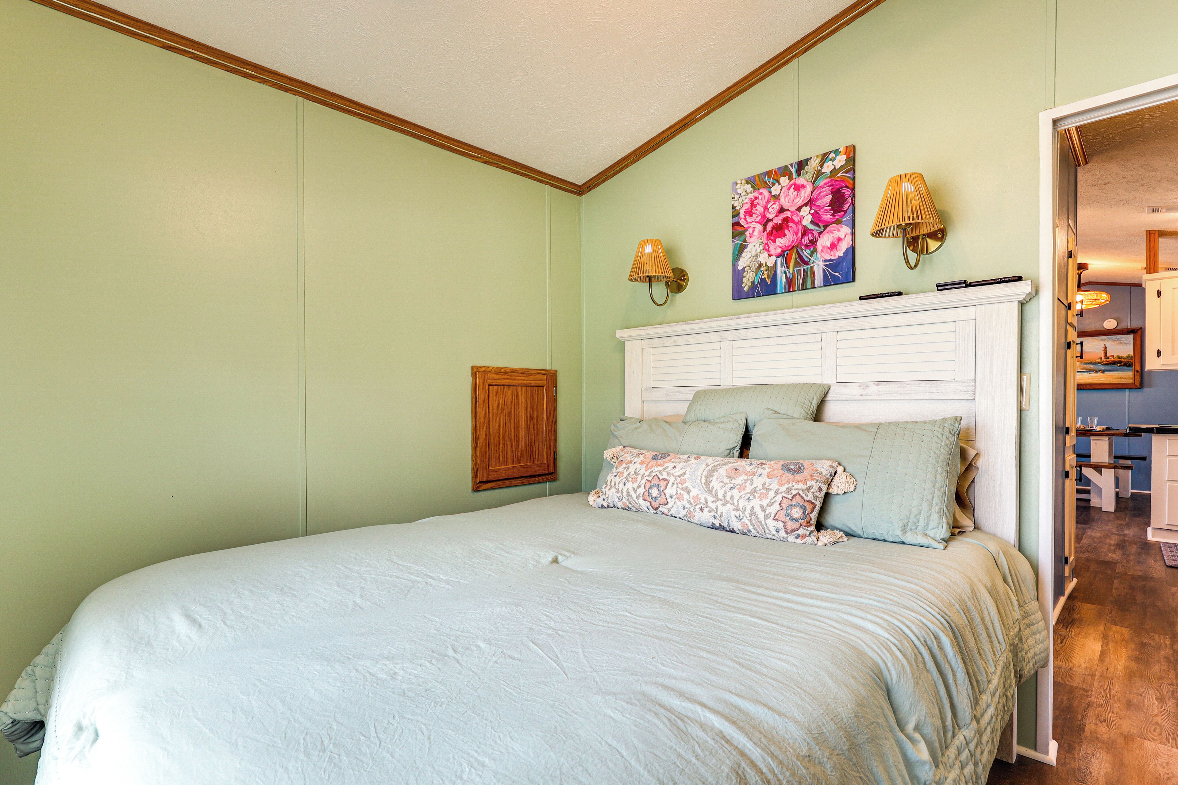 Een slaapkamer met een bed, een houten kast, een wit hoofdeinde en een schilderij aan de muur.