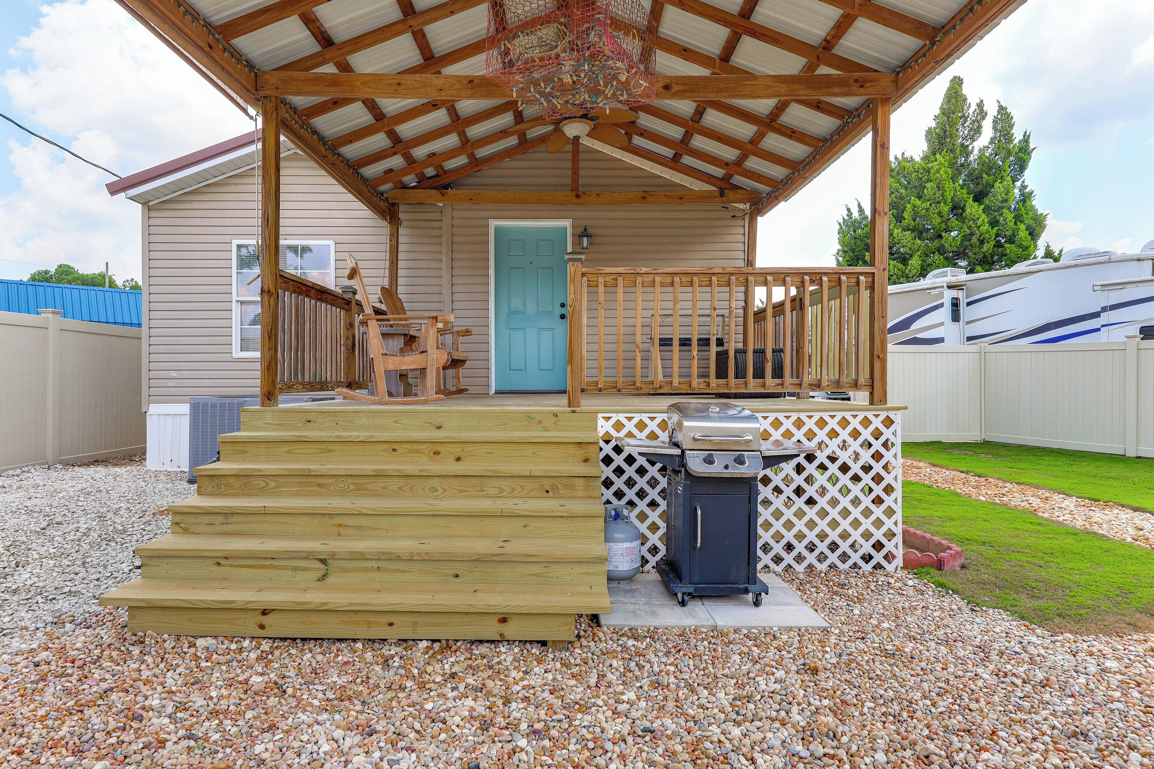 A covered porch with a grill and steps leading to a door.