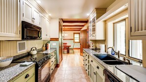A kitchen with a built-in oven, microwave, and double sink. There is a wooden dining table and chairs in the center of the room. - Lakefront Hamlin Home w/ Fire Pit & Dock (Free Soil)