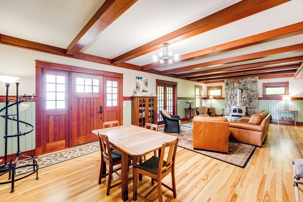 A spacious living area with a wooden dining table, comfortable seating, and a stone fireplace.