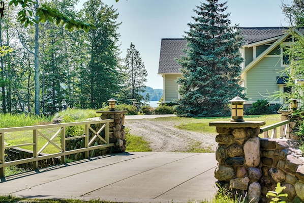 A stone bridge leading to a house with a stone foundation and a light-colored exterior.