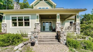 A two-story house with a stone staircase leading to the front door, surrounded by greenery. - Lakefront Hamlin Home w/ Fire Pit & Dock (Free Soil)
