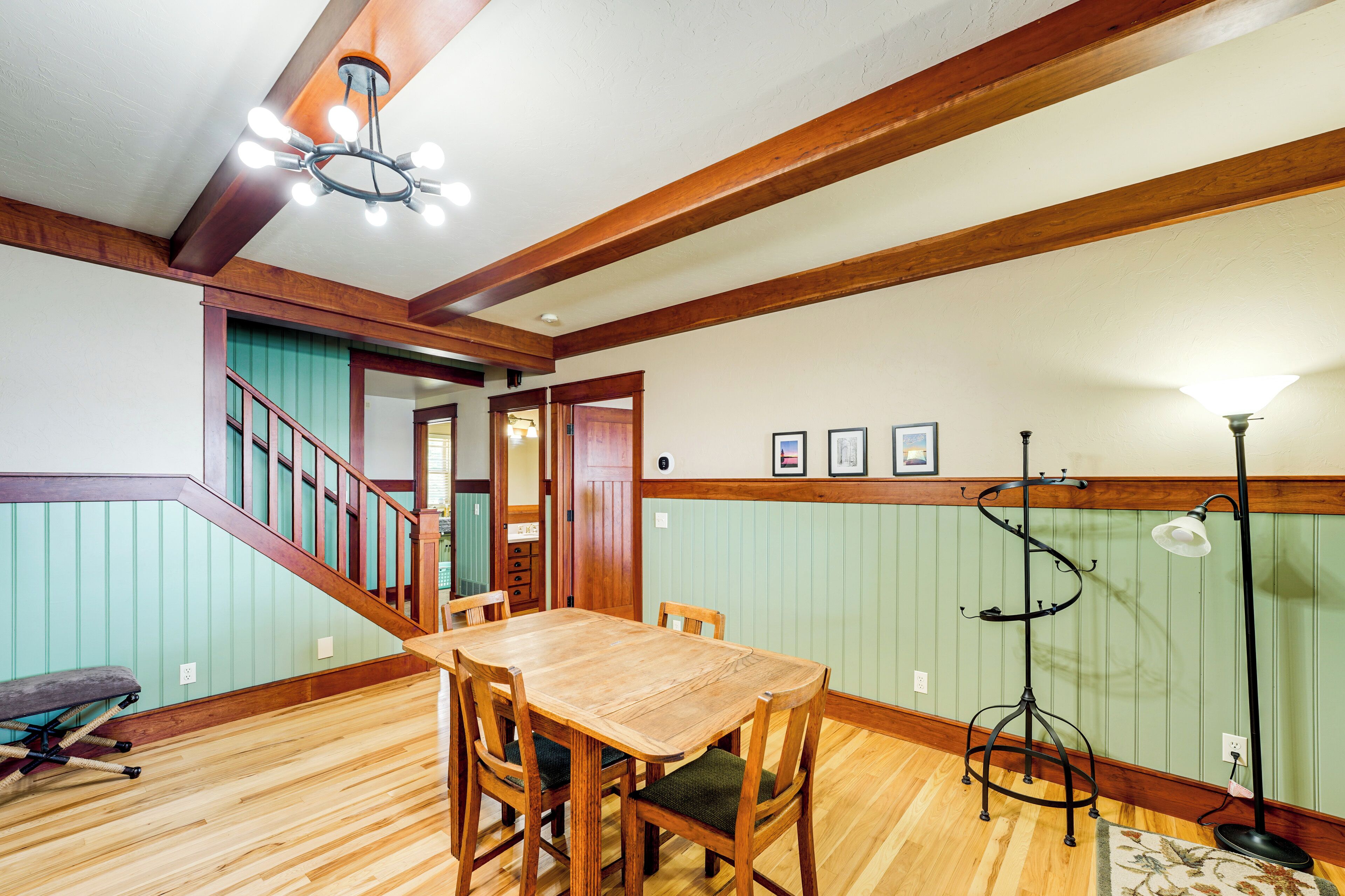 A dining area with a wooden table and chairs, a staircase, and a floor lamp.