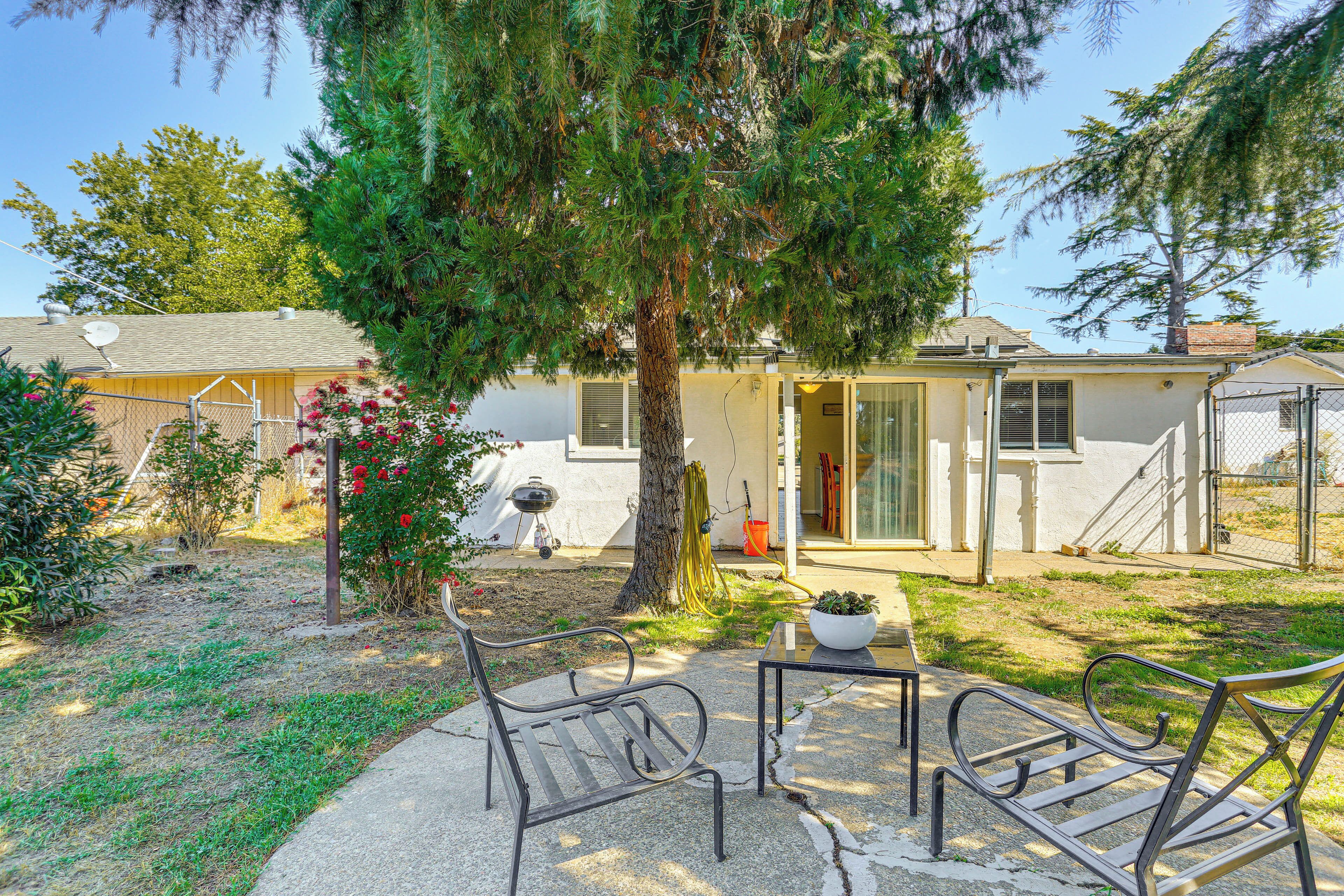 A house with a patio area featuring two metal chairs and a small table.