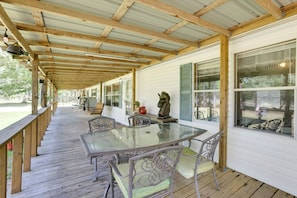 A covered outdoor patio with a glass table and chairs, wooden beams, and a view of the surrounding area. - Play Games, Bike & Unwind: Cleveland Family Home! (Cleveland)