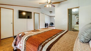 Una camera da letto con un letto grande, un ventilatore a soffitto e una televisione appesa al muro.