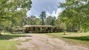 Un rustico chalet con veranda, circondato da alberi e un prato.