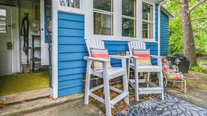 Una casa blu con veranda, con due poltrone Adirondack bianche e cuscini colorati.