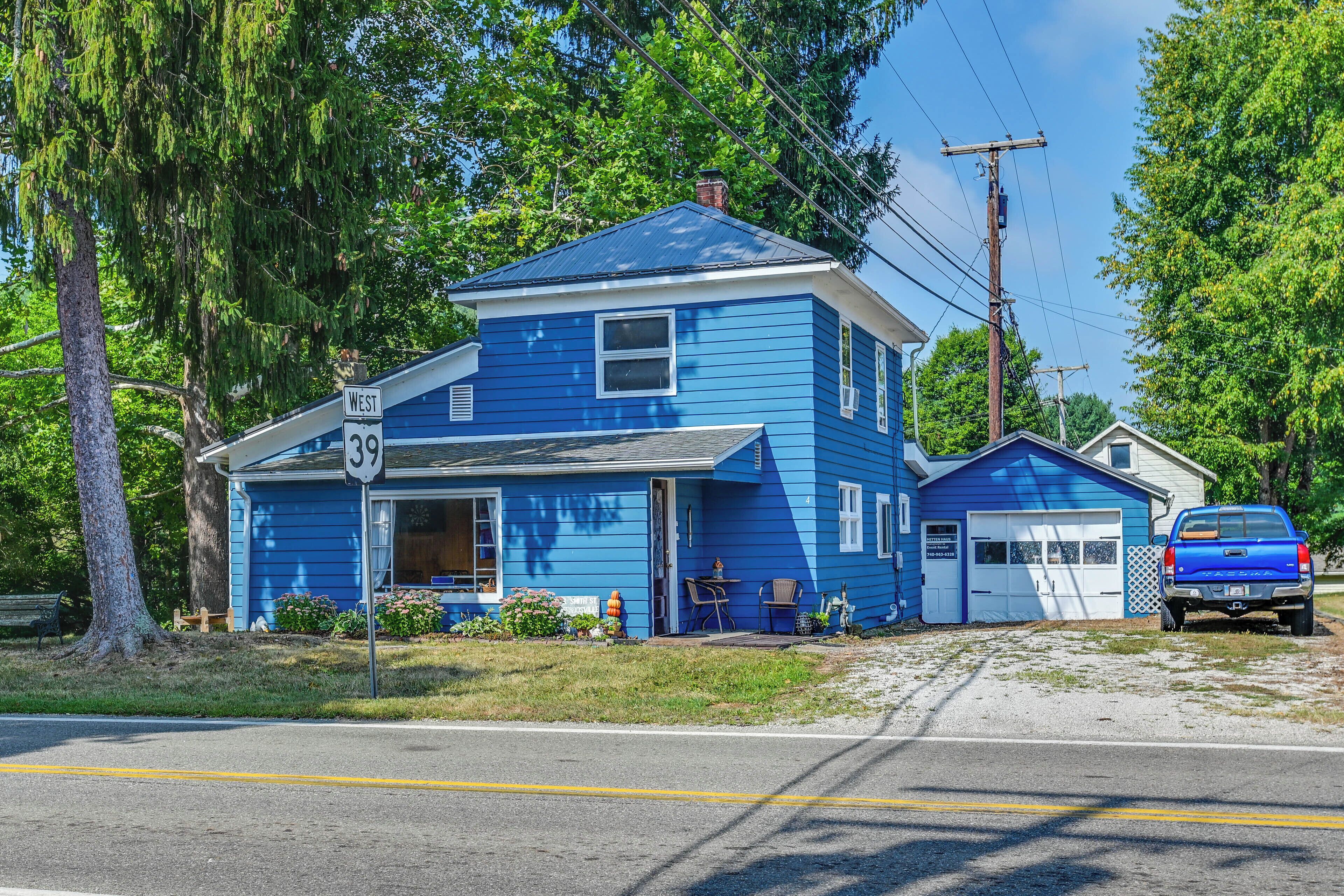Une maison bleue à deux étages, avec un garage, une allée et un camion bleu garé devant.