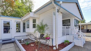 A white single-story house with a covered porch and a small garden area with plants and rocks. - 1 Mi to Birch Bay SP! Cozy Cabin w/ Pool Access (Blaine)