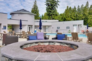 A poolside area with lounge chairs, a fire pit, and a building with a pool. - 1 Mi to Birch Bay SP! Cozy Cabin w/ Pool Access (Blaine)