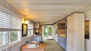 A narrow kitchen with a dining area, white cabinets, and a view through the door. - 1 Mi to Birch Bay SP! Cozy Cabin w/ Pool Access (Blaine)