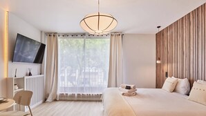 Un dormitorio con cama, televisor, escritorio y silla.