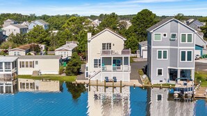 Une propriété située au bord de l’eau, dotée d’un quai, d’une maison avec balcon et d’un bateau.
