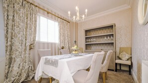 A dining room with a table set for four, a chandelier, and a decorative shelf with glassware. - Pier View House - Blackpool (Blackpool)