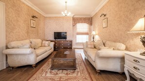 A living room with two sofas, a coffee table, a TV, and a window with curtains. - Pier View House - Blackpool (Blackpool)