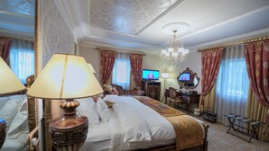 A luxurious hotel room with a large bed, ornate lamps, a television, and a chandelier. - House of splendor Boutique Hotel (Lagos)