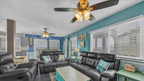 A living room with a sectional sofa, a coffee table, and a ceiling fan. - Sunskipper Panoramic Ocean Front - 2br oceanfront condo in Carolina Beach (Carolina Beach)