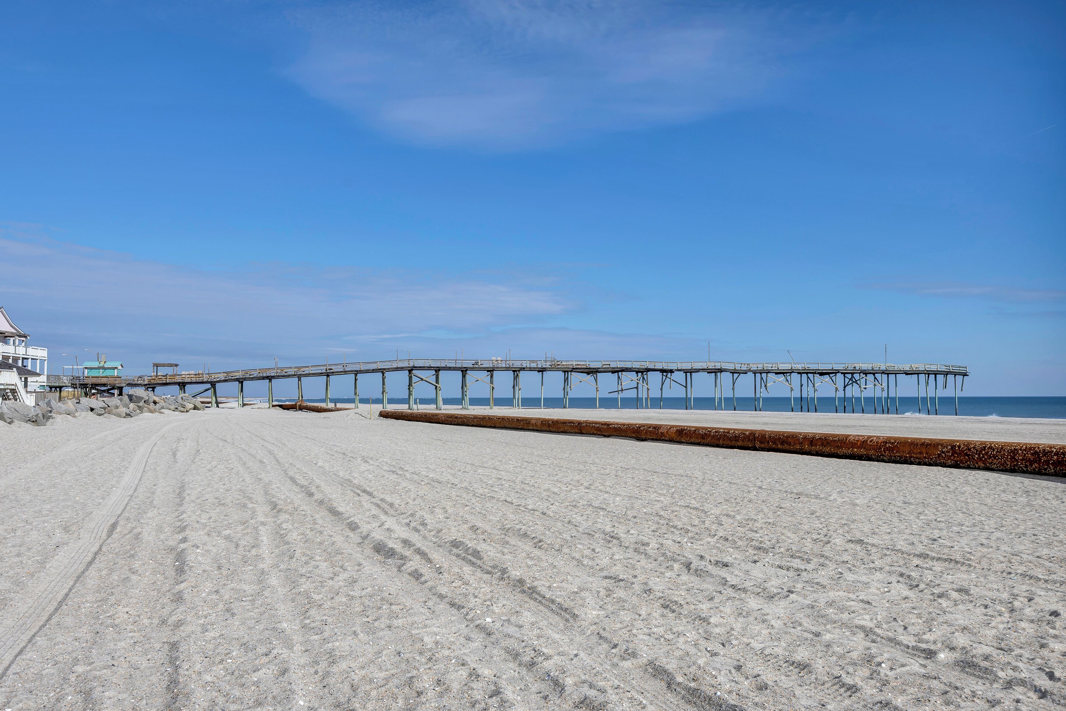 Une plage avec une jetée qui s’avance dans l’océan.