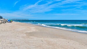 A beach with a pier extending into the ocean, sandy shore, and a clear blue sky. - Sunskipper Panoramic Ocean Front - 2br oceanfront condo in Carolina Beach (Carolina Beach)