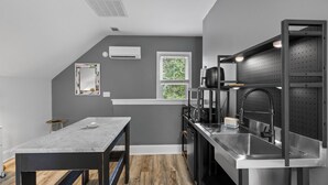 Een moderne keuken met een marmeren aanrecht, roestvrijstalen apparatuur en een prikbord achterwand.
