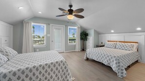 A bedroom with two beds, a ceiling fan, and a view of the outside.