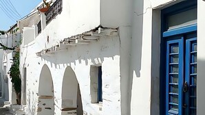 Une rue étroite bordée de bâtiments blancs, de portes bleues et d’un pavé de pierre.