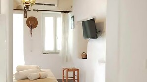 Une chambre à coucher avec un lit, une chaise en bois, un téléviseur fixé au mur et un luminaire au plafond.