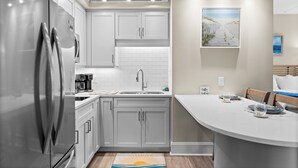Una cocina moderna con electrodomésticos de acero inoxidable, armarios blancos y una barra desayunadora.