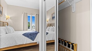 Habitación de hotel con dos camas, cabecero de madera, balcón con vistas y un espejo que refleja la habitación.