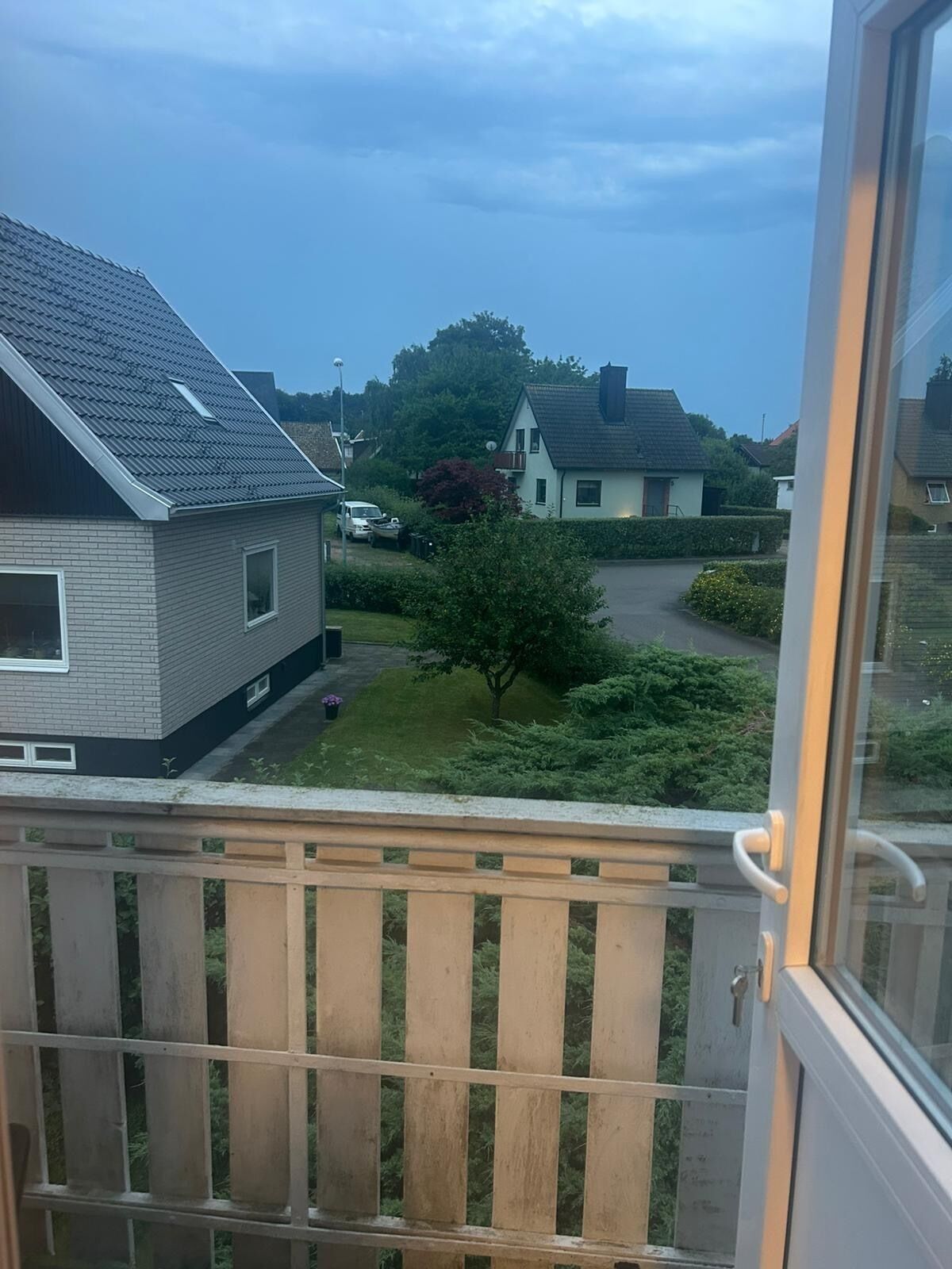Un quartier résidentiel avec des maisons, un petit arbre et une allée pavée.