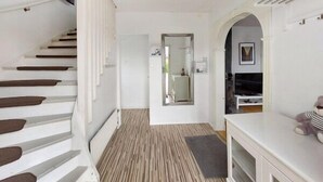 A staircase with wooden steps and white walls, leading to a room with a mirror, a small table, and a television. - Charming 4-bedroom house with AC in Skåne län (Skåne län)