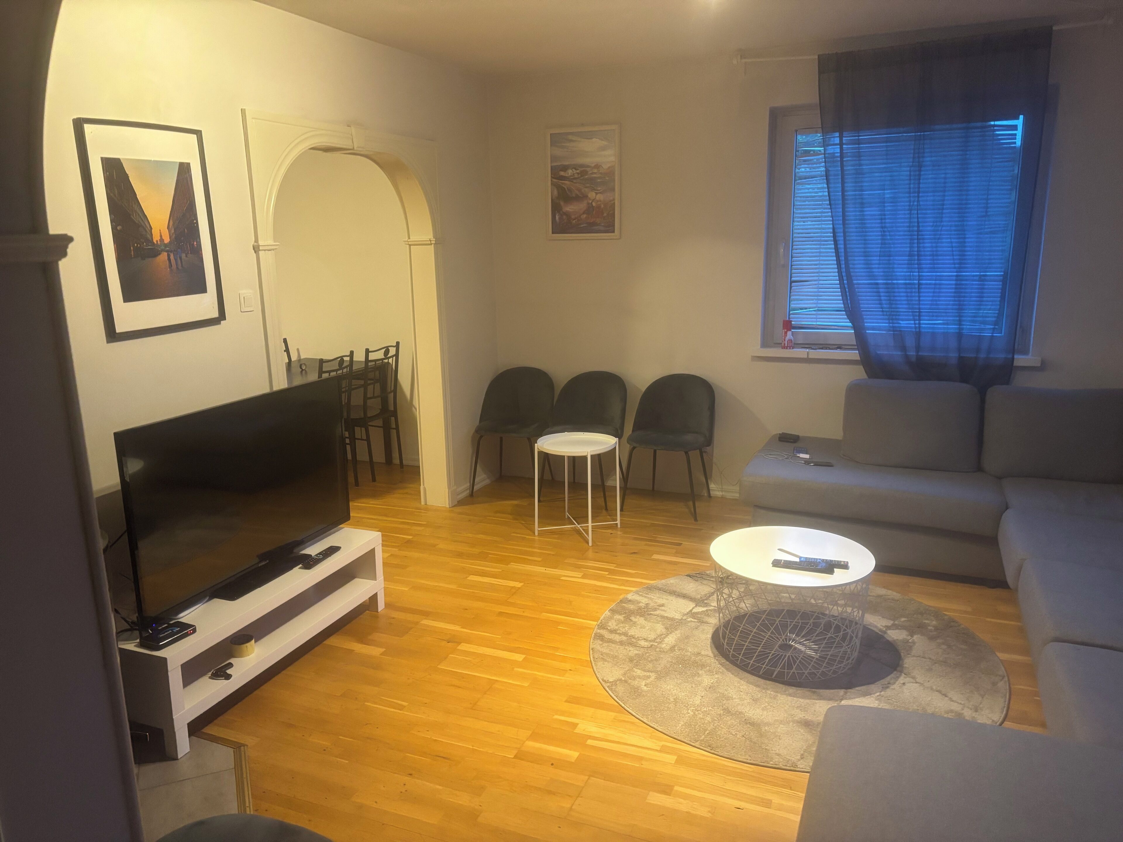 Un salon comprenant un téléviseur, un canapé, des fauteuils et un coin repas.