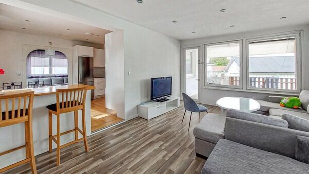 A modern living room with a grey sofa, wooden chairs, a small table, and a TV. - Charming 4-bedroom house with AC in Skåne län (Skåne län)