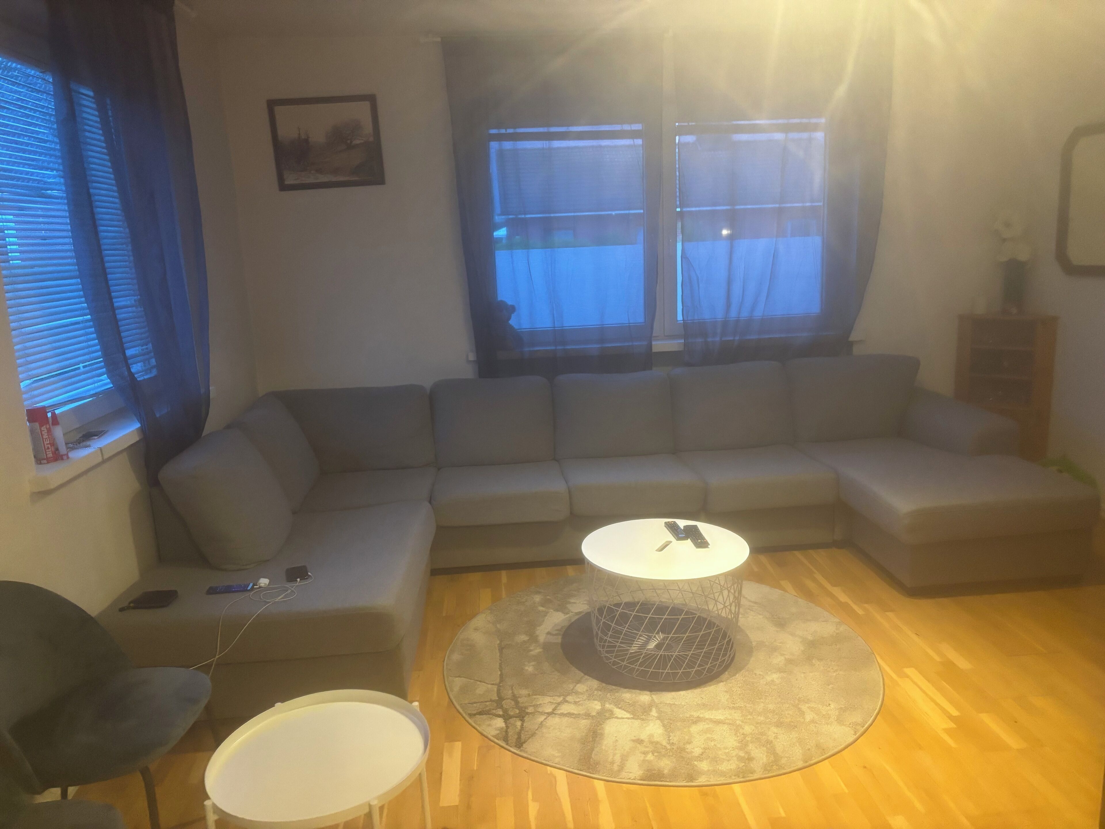 Una sala de estar con un sofá modular, una mesita redonda y una mesita auxiliar.