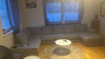 Una sala de estar con un sofá modular, una mesita redonda y una mesita auxiliar.