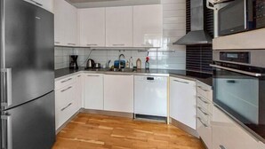A modern kitchen with white cabinets, a stainless steel refrigerator, a dishwasher, and a built-in oven. - Charming 4-bedroom house with AC in Skåne län (Skåne län)
