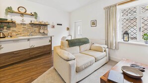 A cozy living room with a sofa, a coffee table, and a window with a view. - Host & Stay | Brackenrigg Cottage (Rothbury)