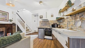 A modern kitchen with a stone backsplash, wooden cabinets, and a built-in oven. - Host & Stay | Brackenrigg Cottage (Rothbury)