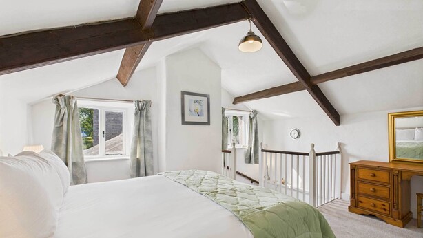 A bedroom with a bed, a dresser, a window, and a ceiling with exposed beams. - Host & Stay | Brackenrigg Cottage (Rothbury)
