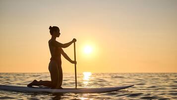 Eine Person steht bei Sonnenuntergang auf einem Paddleboard.