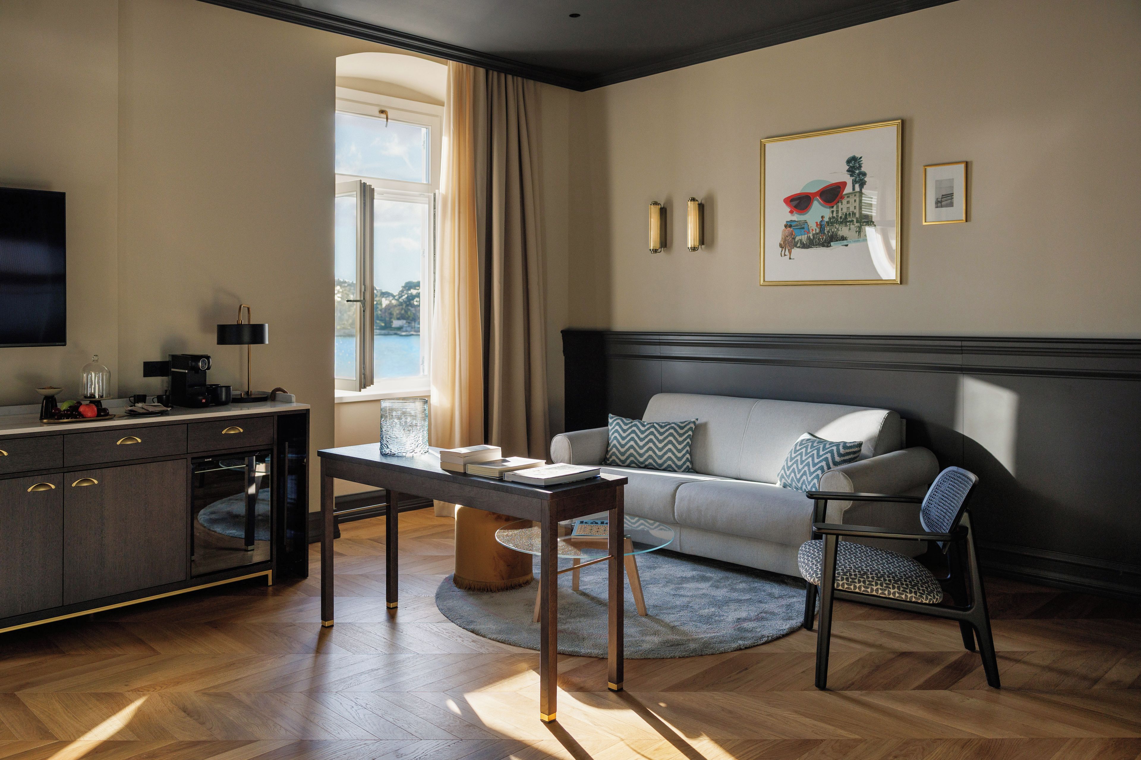 A modern living room with a sofa, a coffee table, a television, and a view of the outdoors.