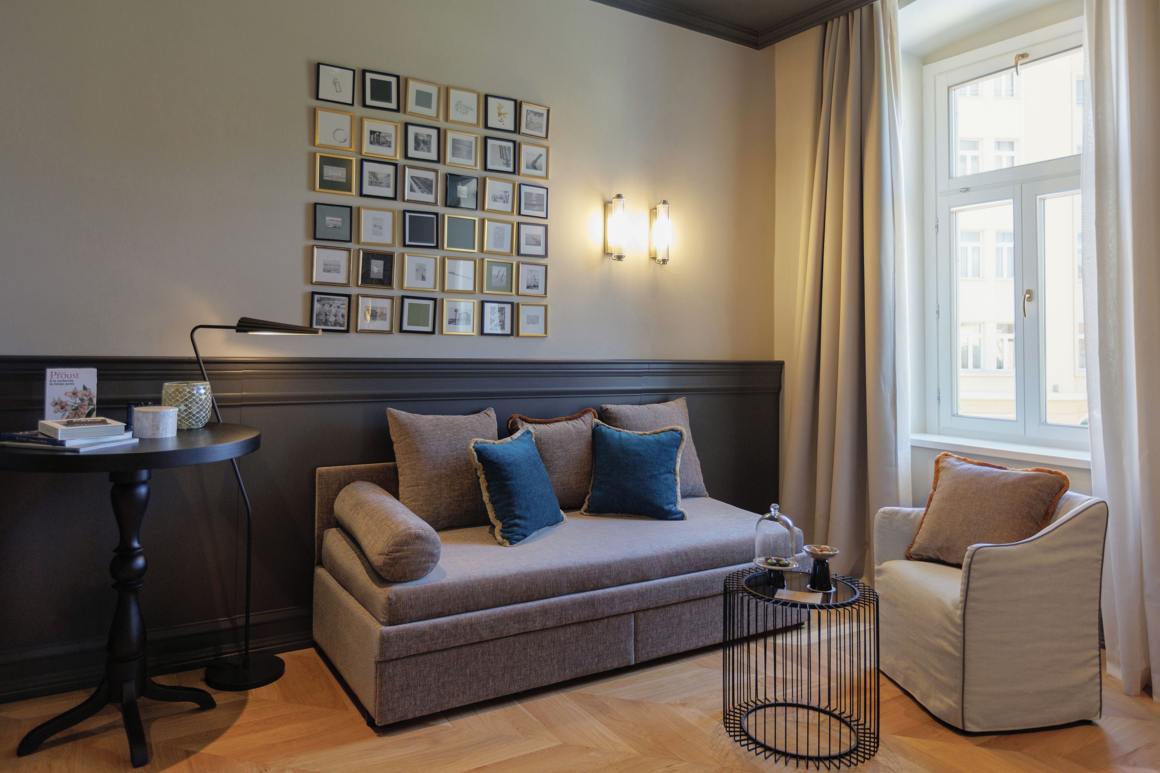 A modern living room with a sofa, armchairs, a coffee table, and a wall of framed pictures.