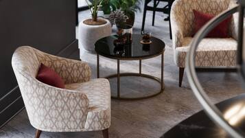 Un área de descanso moderna con sillones estampados, una mesa redonda en el centro y una planta en maceta.