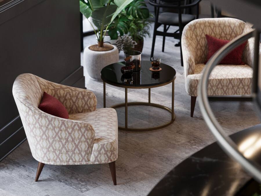 Un área de descanso moderna con sillones estampados, una mesa redonda en el centro y una planta en maceta.