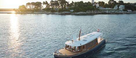A boat with a cabin and deck area, moving on calm water.