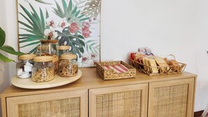 A wooden cabinet with woven baskets, jars, and a framed floral artwork.